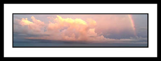 Fluffy cumulus clouds illuminated in the soft pink light of sunset. Off to the side a small rainbow emerges. Sunset Clouds by Alison Thomas of Serenity Scenes Photography and Digital Art.